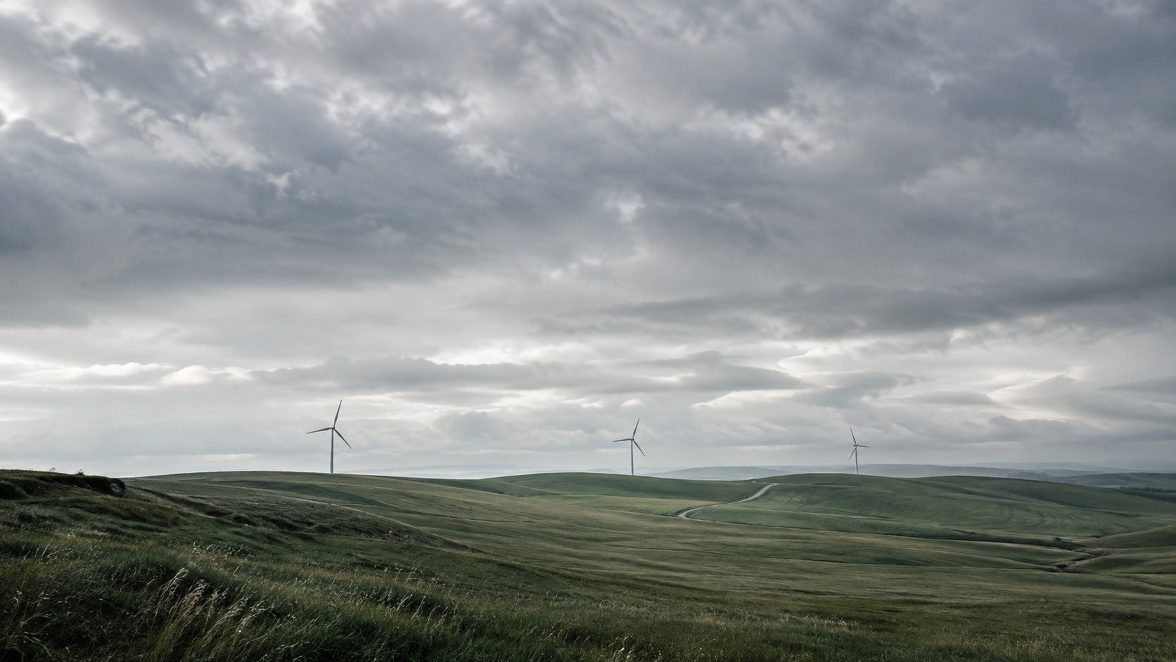 Windräder über grünen Hügeln unter weitem Himmel